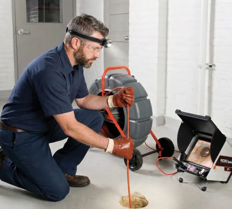 Plumber performing camera inspection of drain pipes